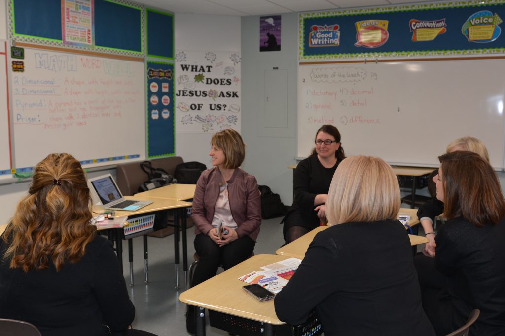 A group of parents gather around a math presentation. 