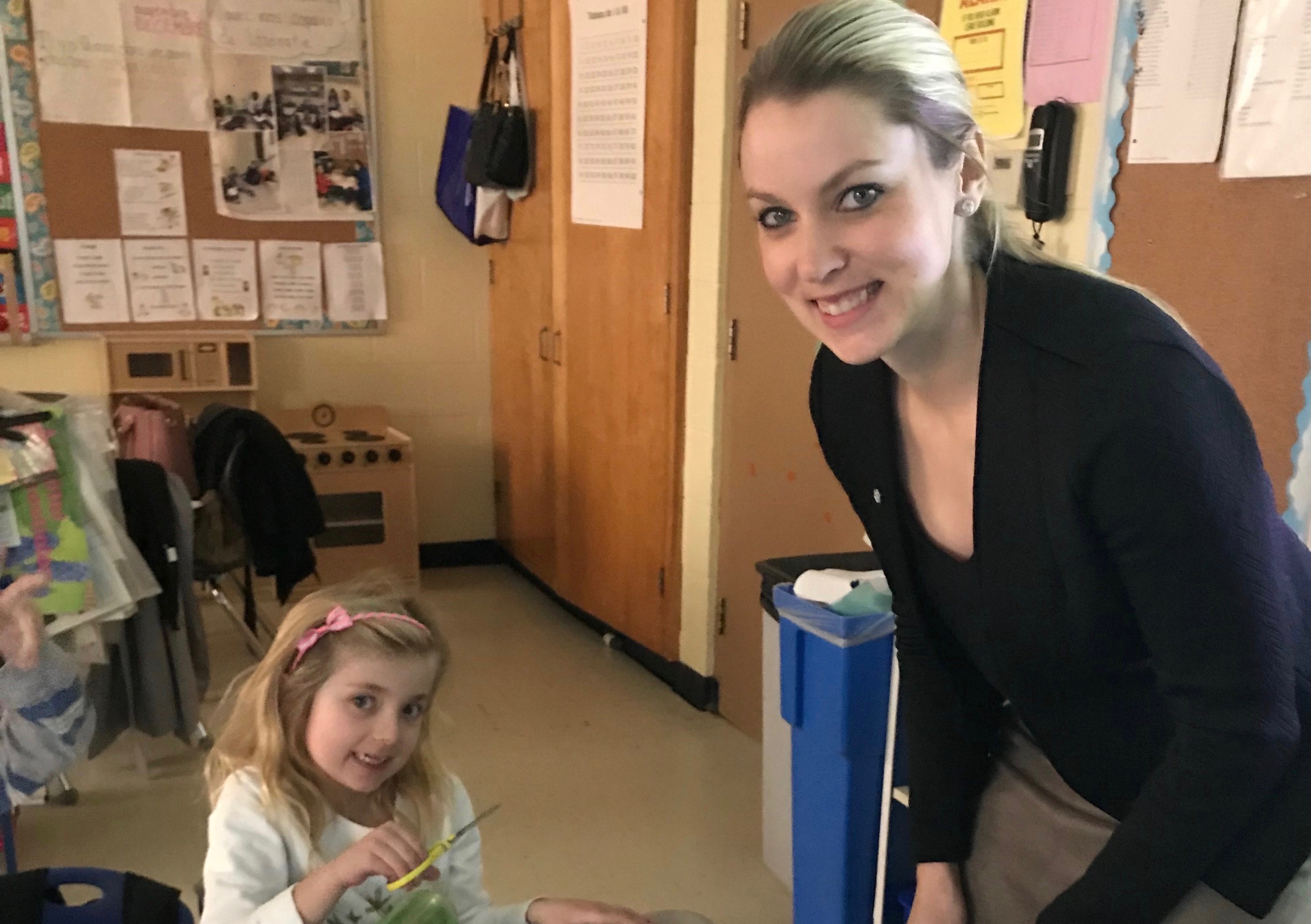 A teacher stands with her student working on an assignment.