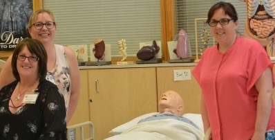 Principal of St. Alberts School stands with the PSW teachers in the PSW classroom alongside a fake patient used to practice and testing.