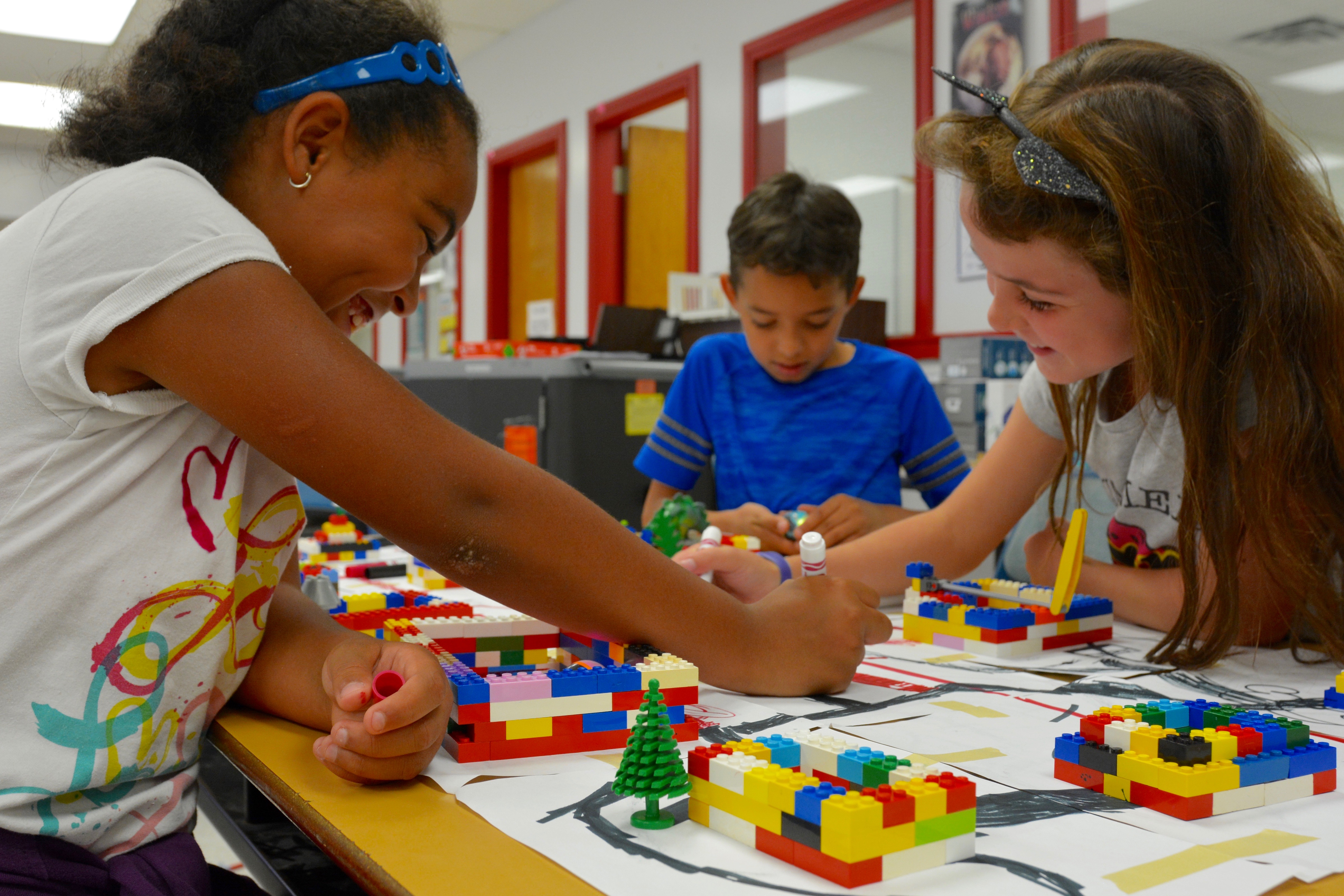 Students Laney, Madelynn and Darius complete an activity with Legos, colouring markers and ozo bots to demonstrate the importance of engineering.