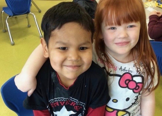 Two Kindergarten students stand smiling.