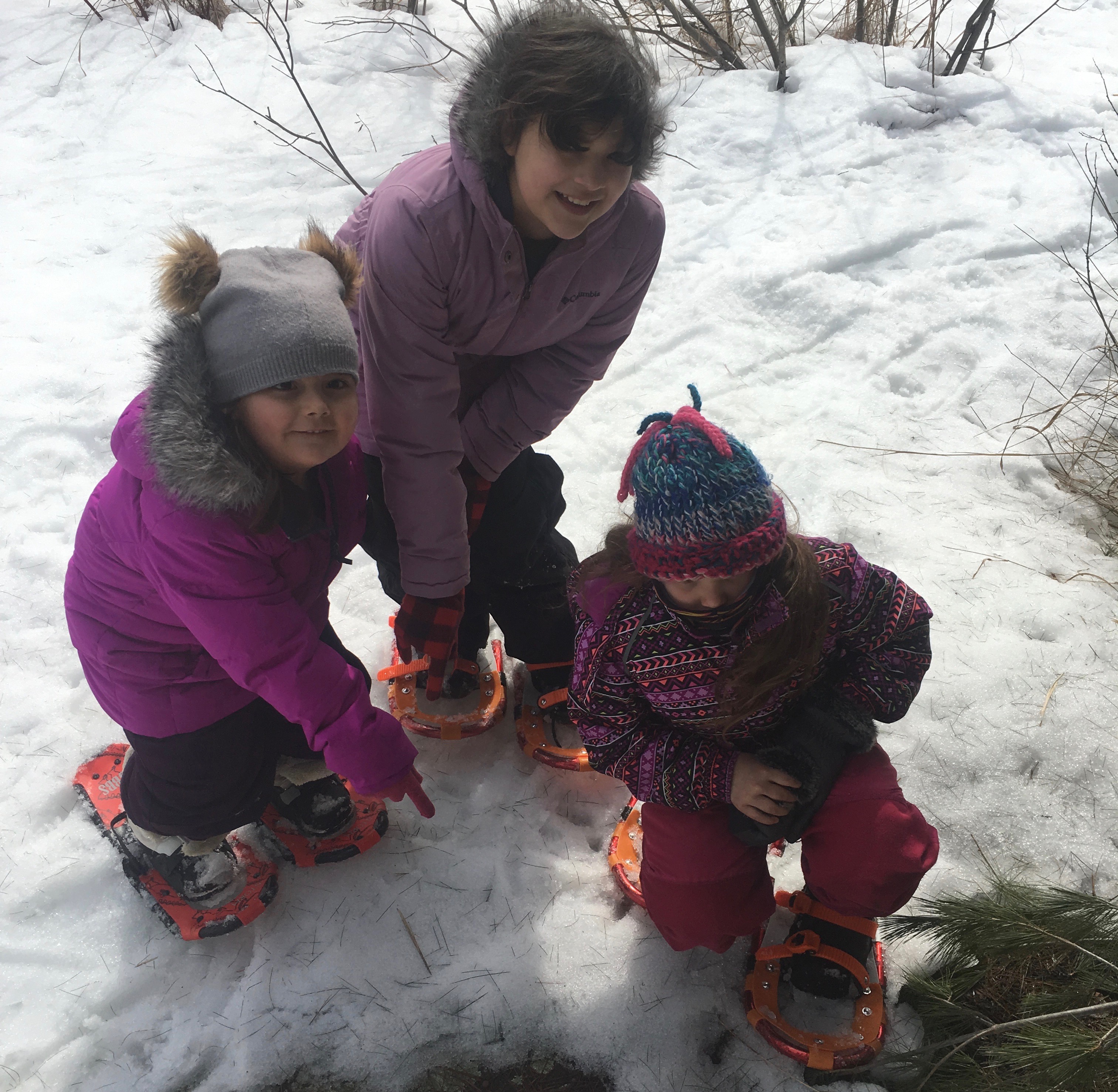 Three students kneel down in the snow