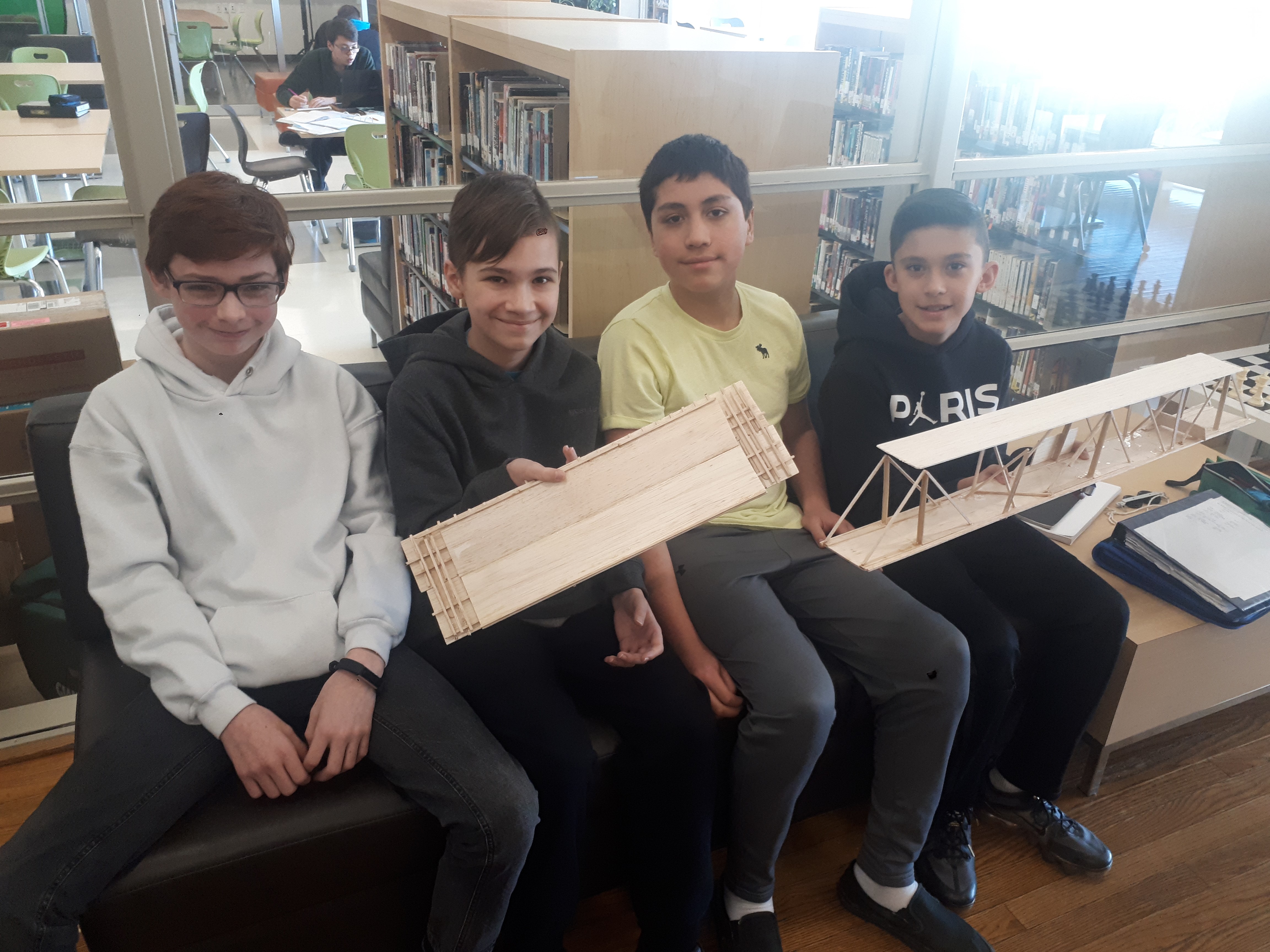 Students sit with their bridge designs