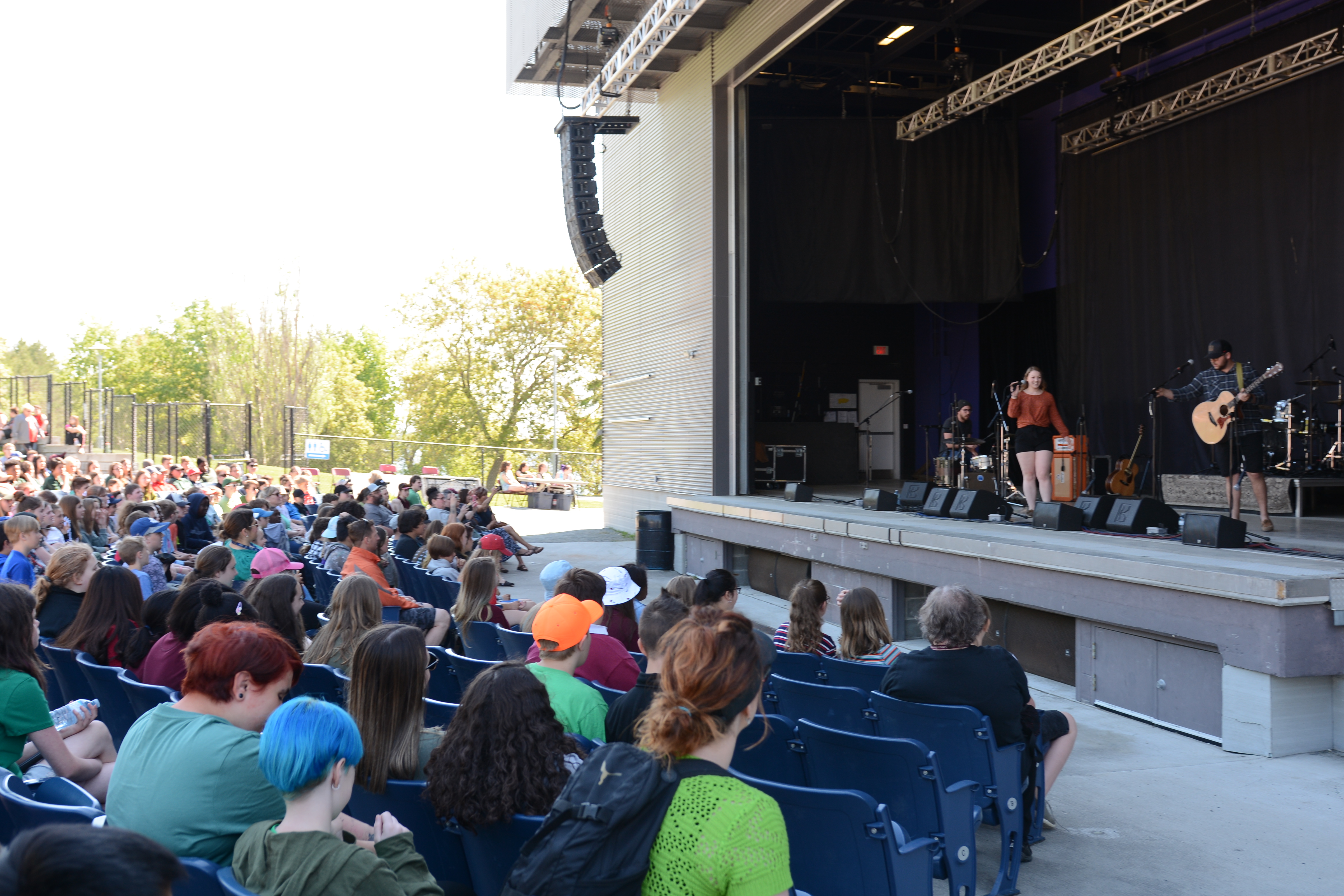 A large audience watches a girl singing onstage.