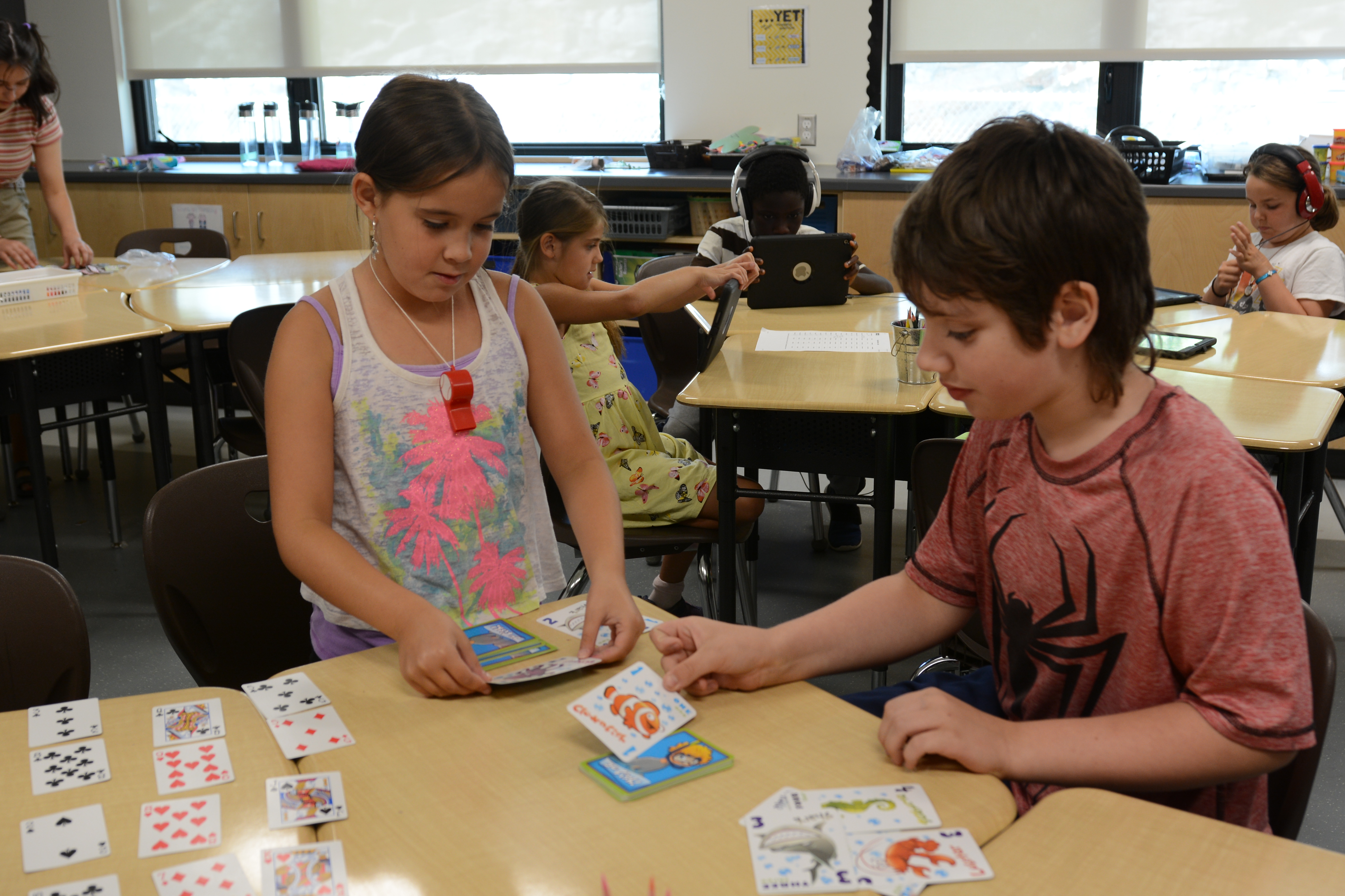 Two students work on their addition by playing a card game.