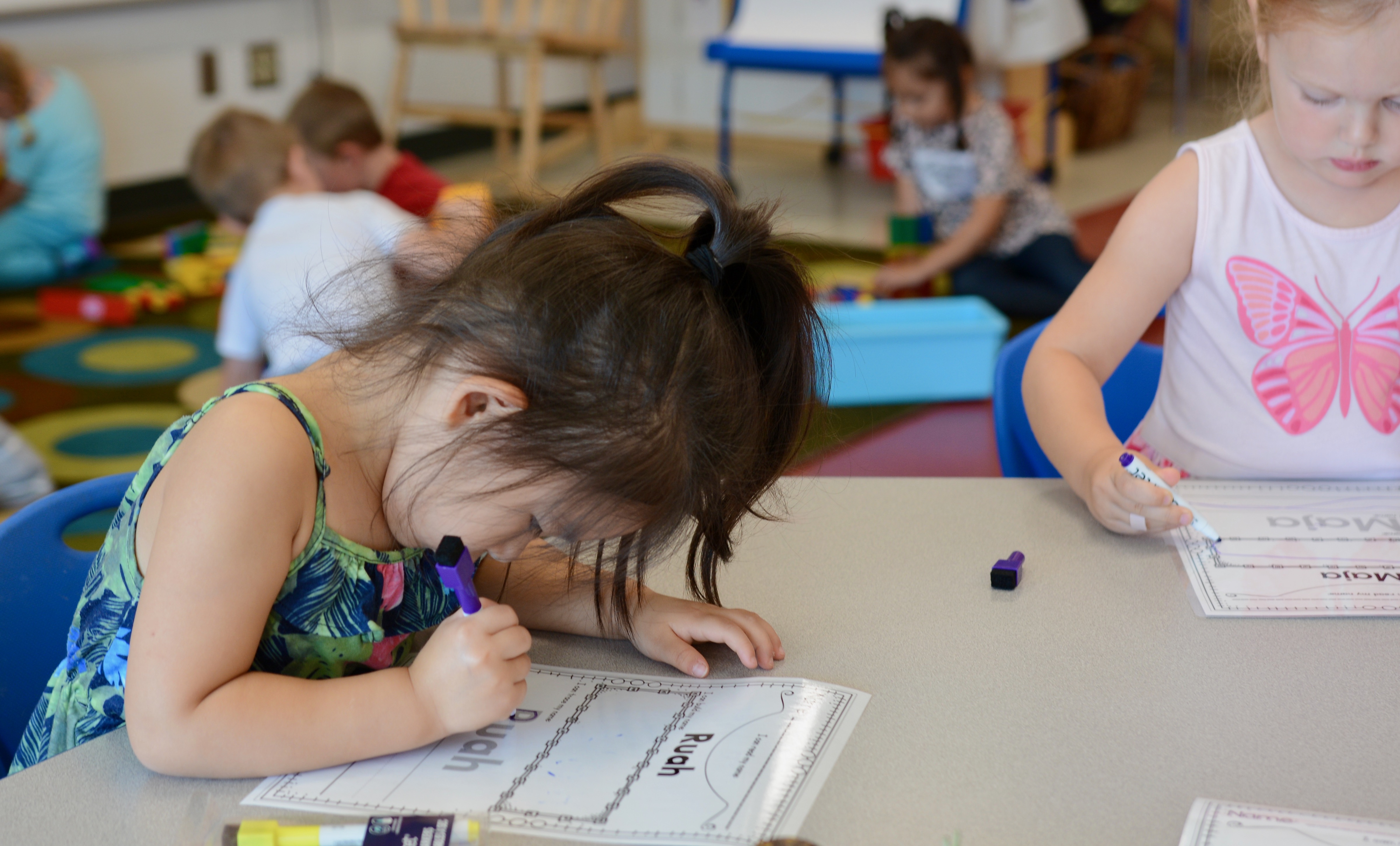 A young girl practices writing out her name.