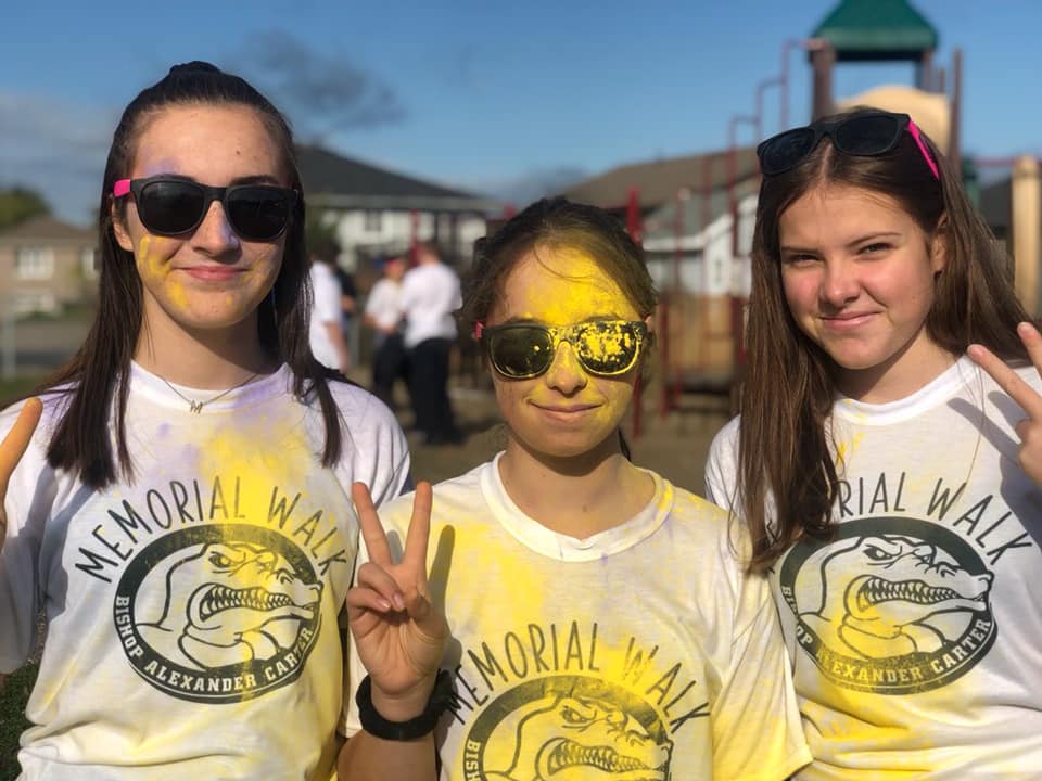 Three girls stand and smile in their Memorial Walk T-shirts