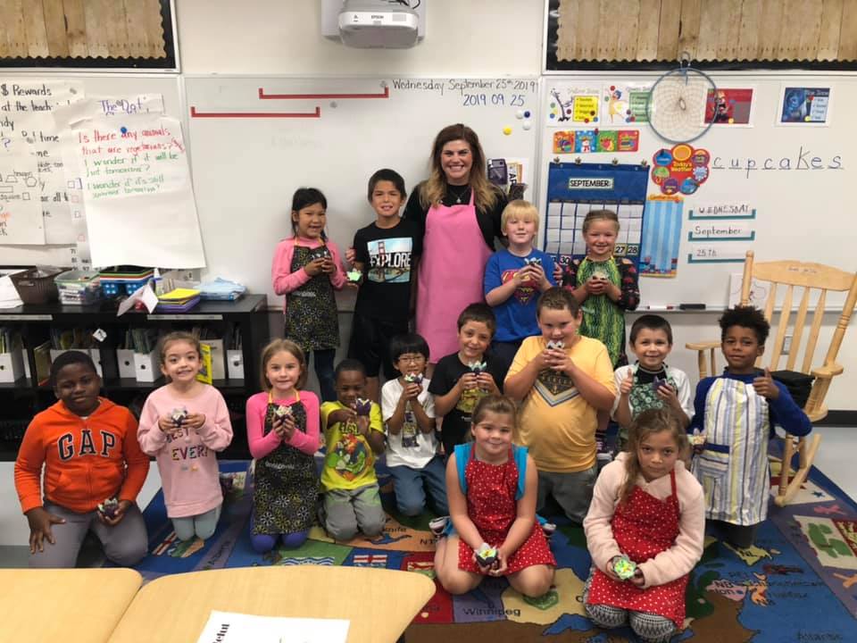 Students and their teacher stand proudle with their rainbow cupcakes.