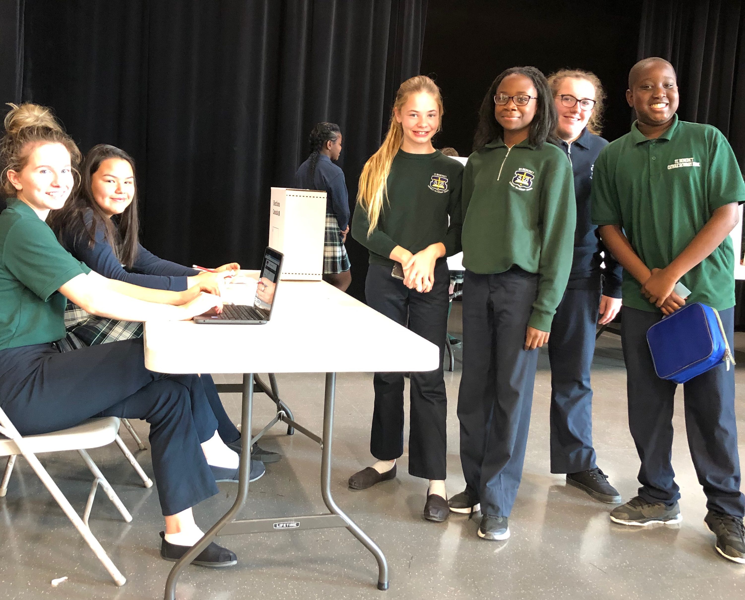 A group of students stand in line by the election booth.