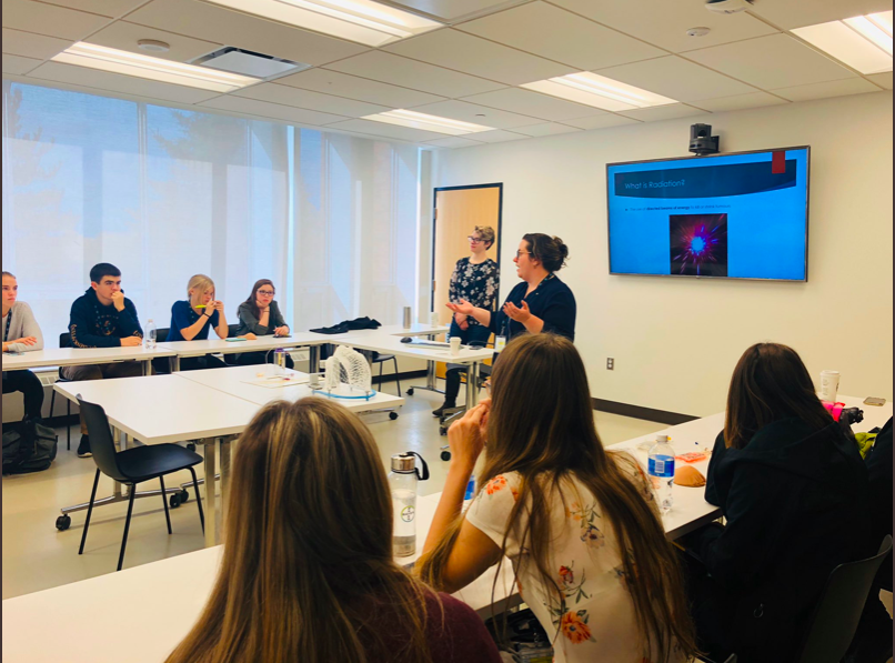 A scientist presents in front of students about a career in oncology.