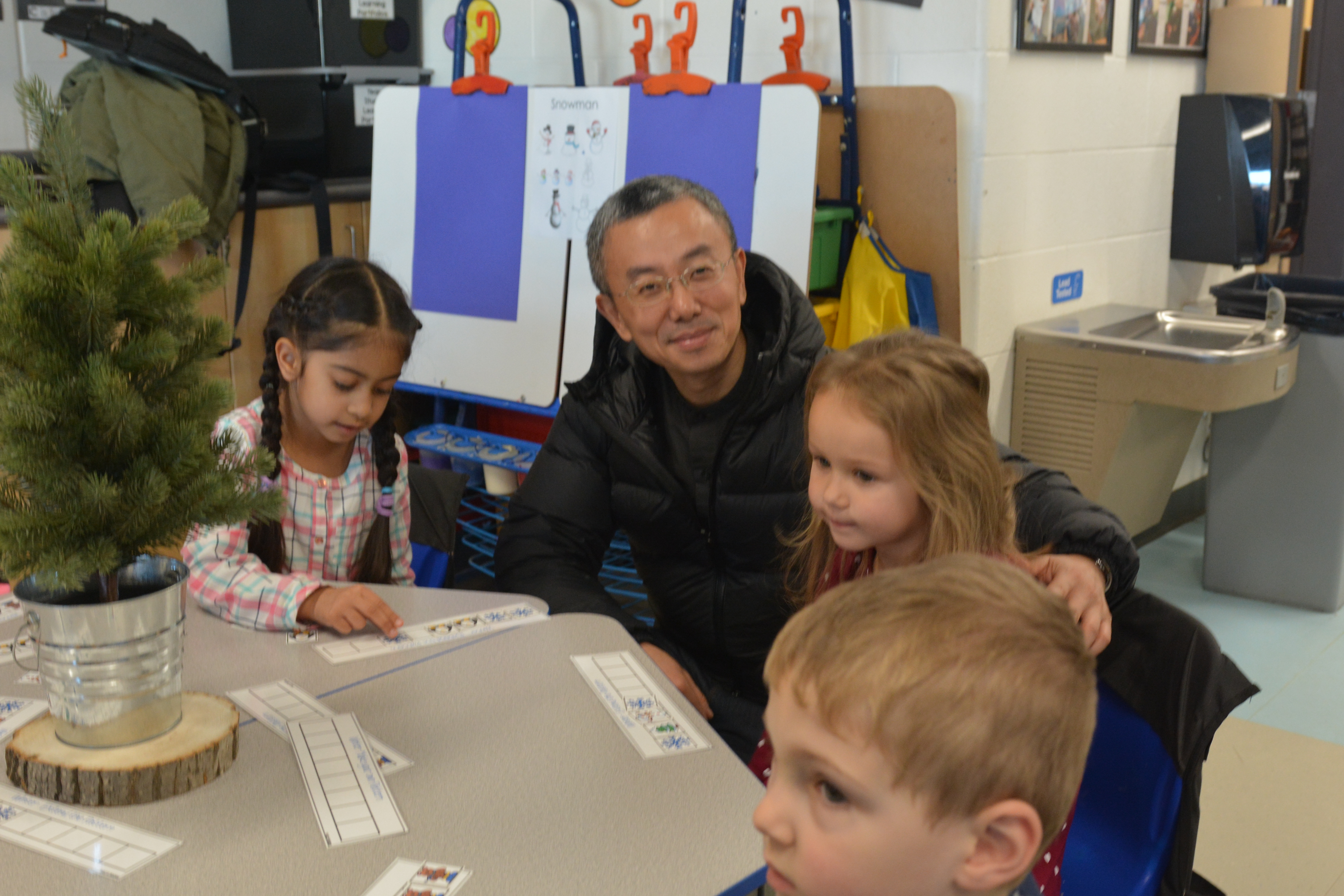 Trade Commissioner Peter Liao works with students at their desks.