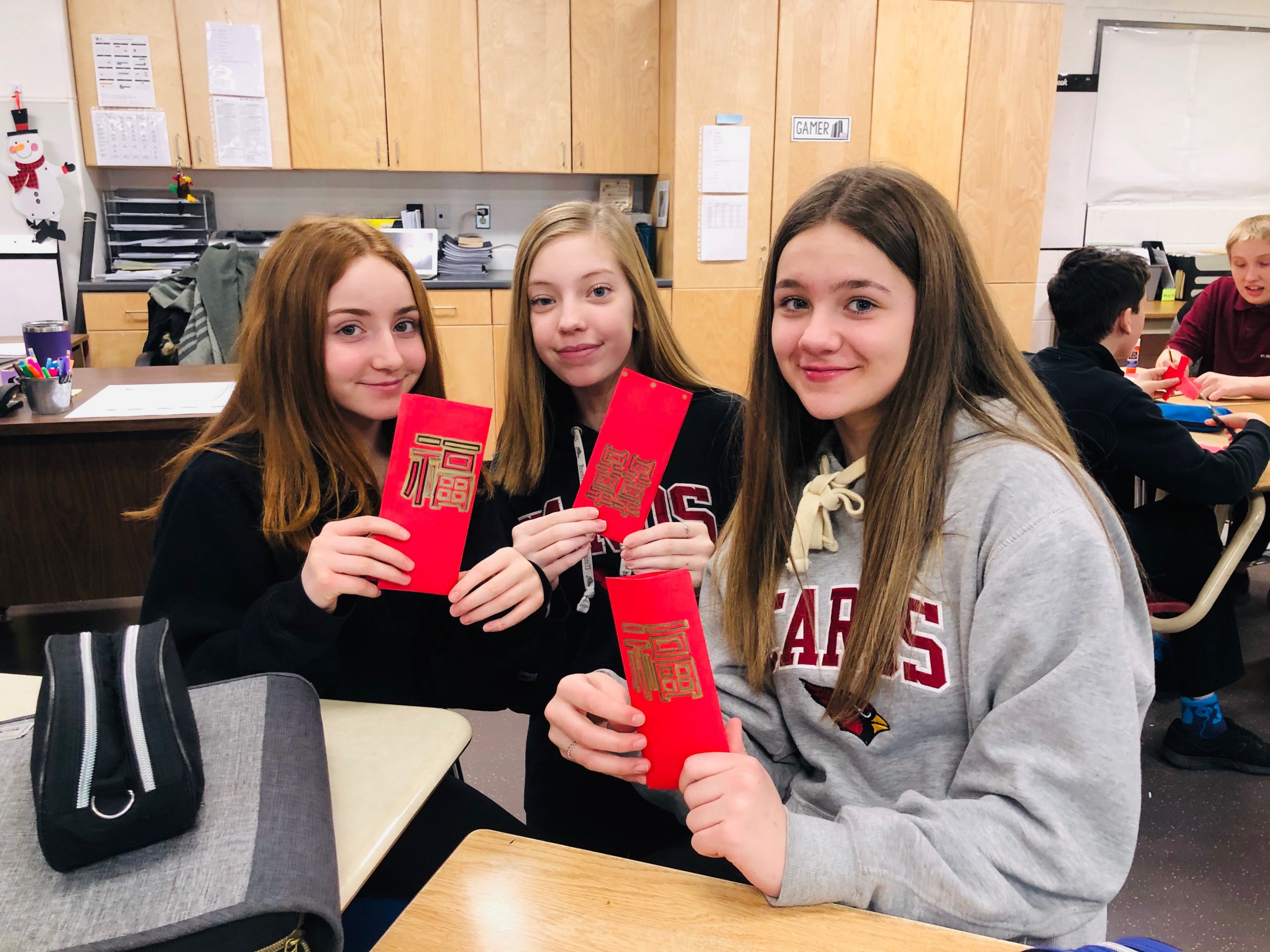 Girls hold up red envelopes