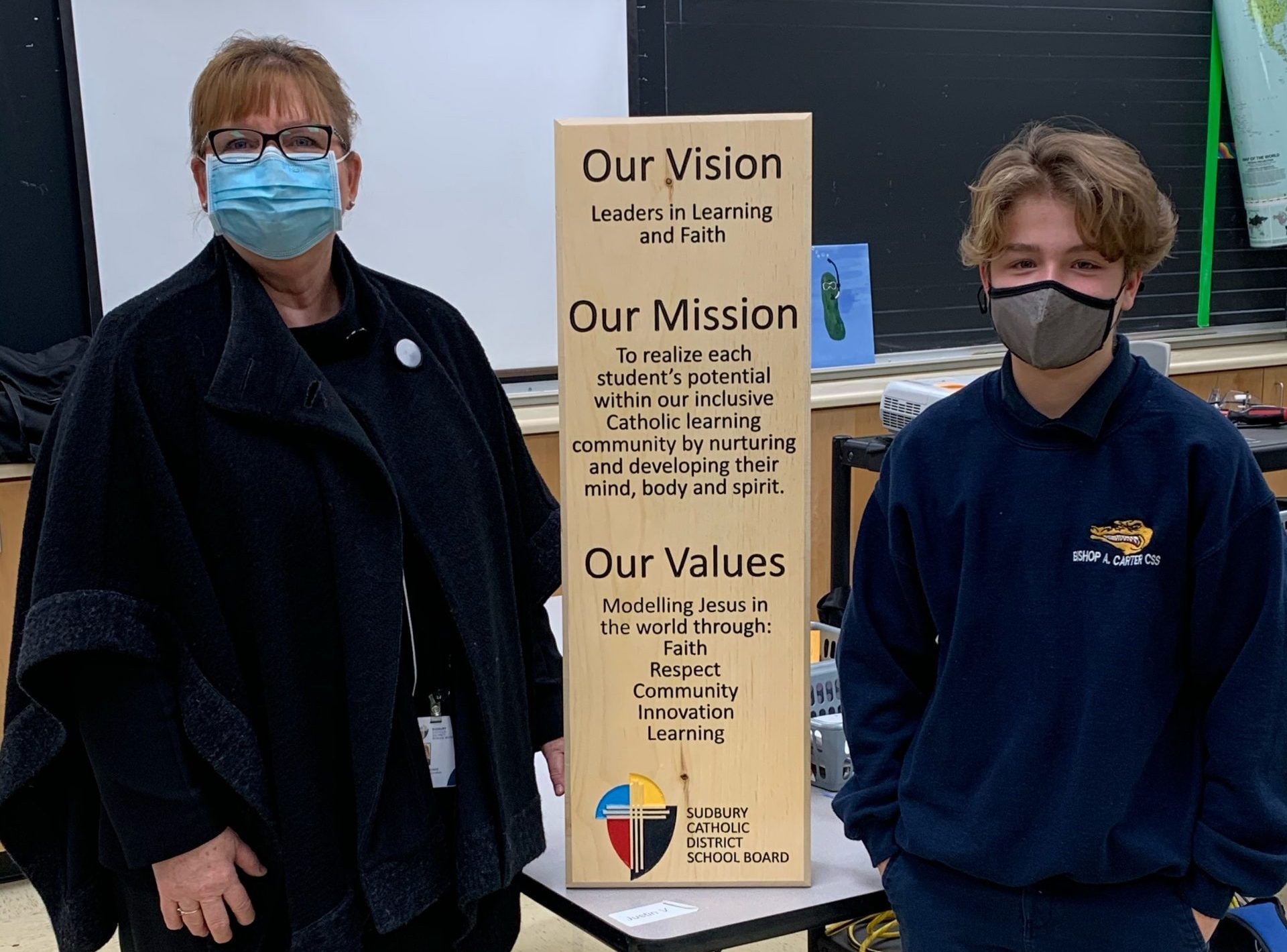 Director and student stands with the wooden plaque