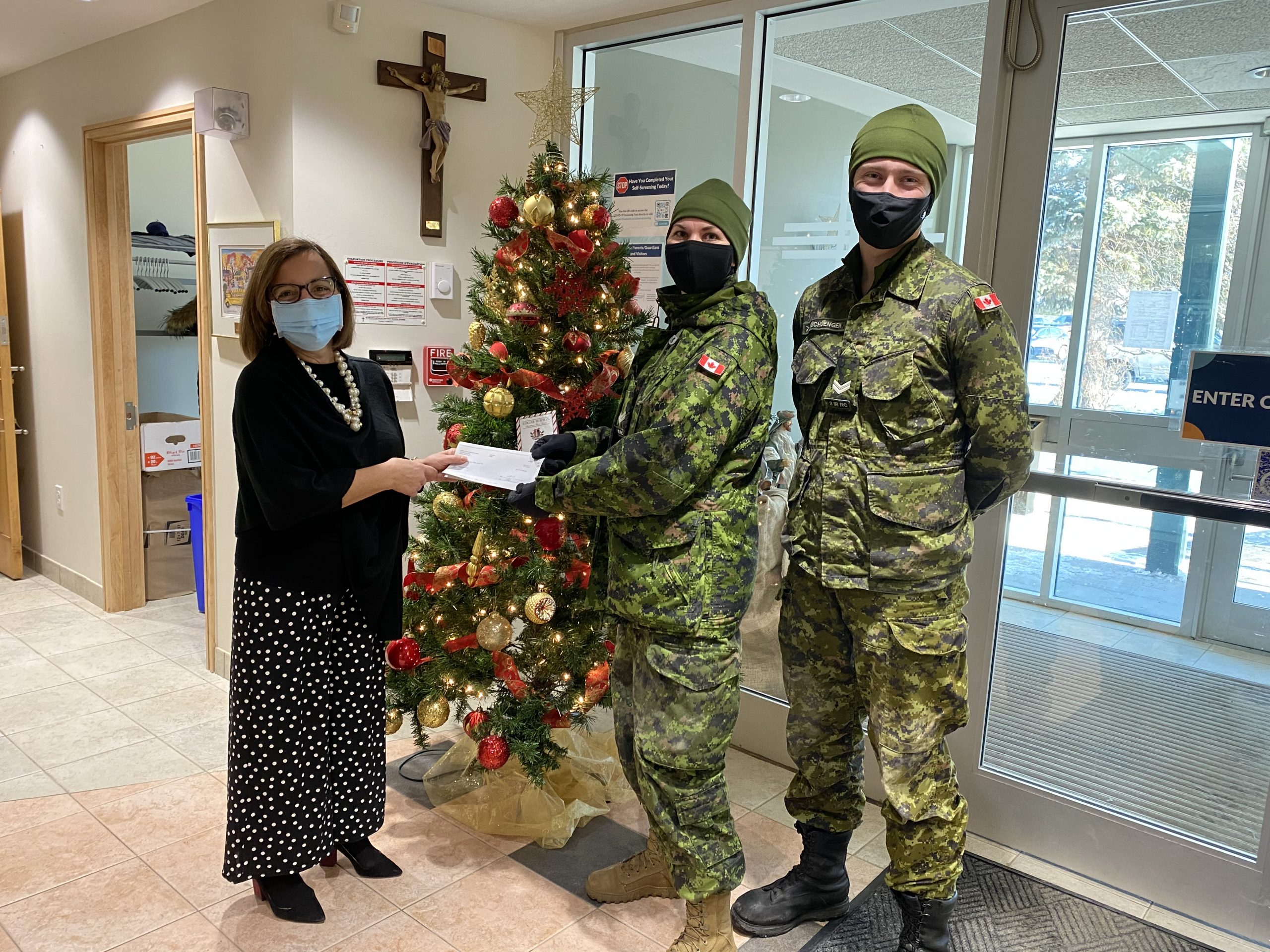 Women hands off cheque to members of the army.