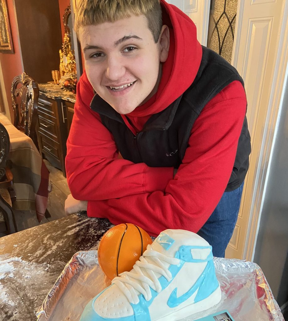 A boy stands next to his cake.