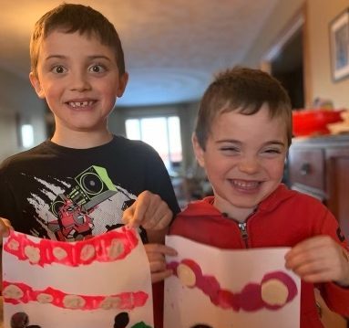 Two boys hold up artwork.