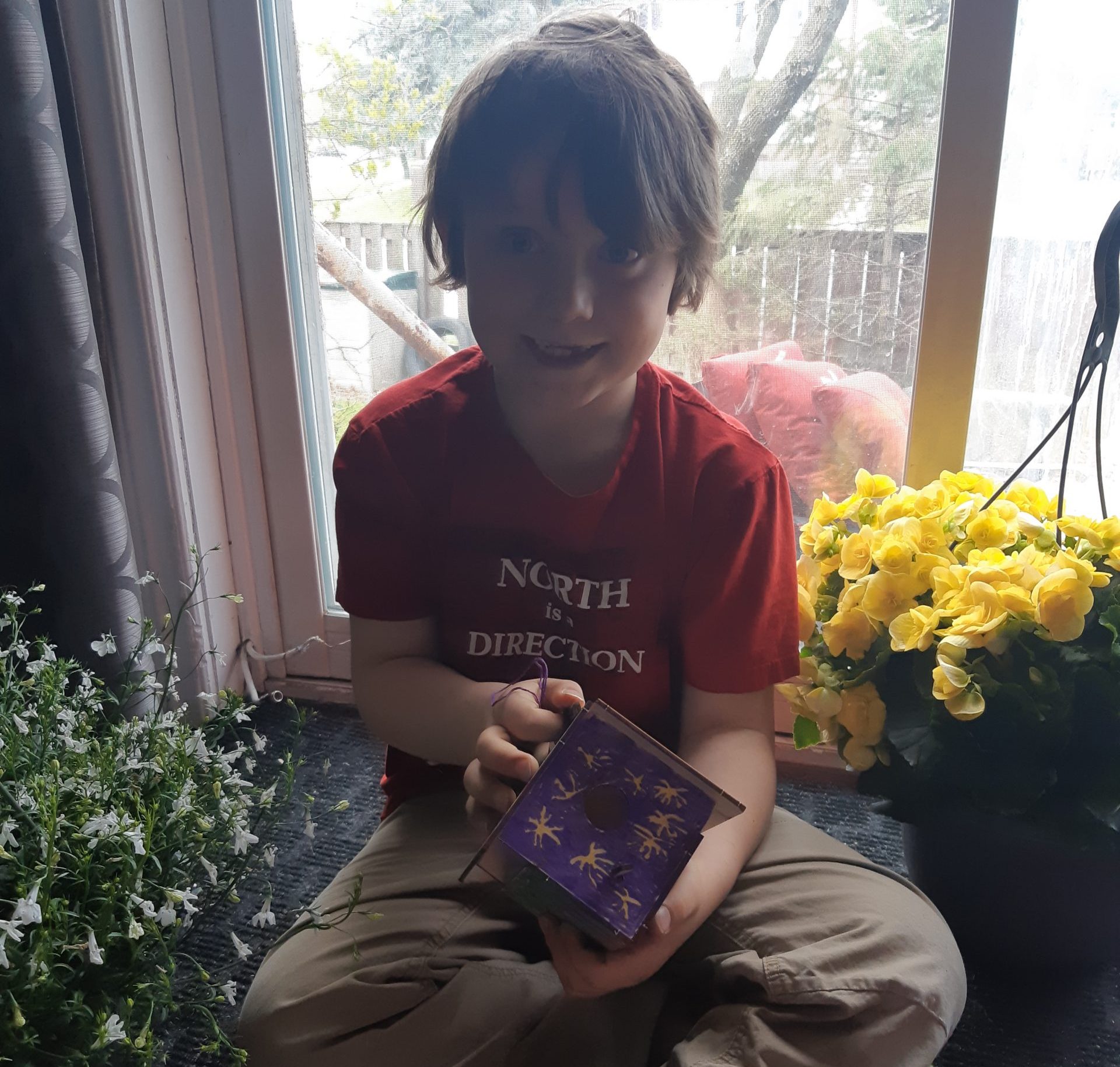 Boy holds up birdhouse