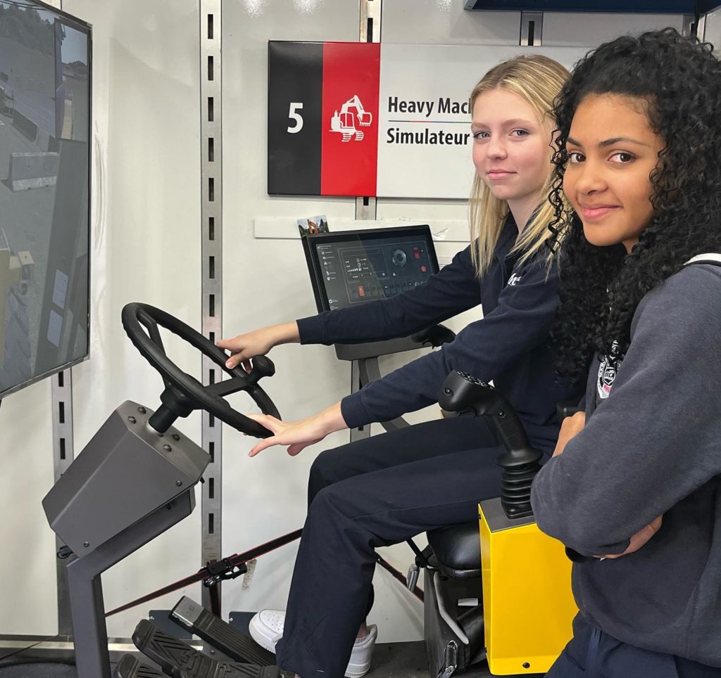 Two girls sit at a simulator