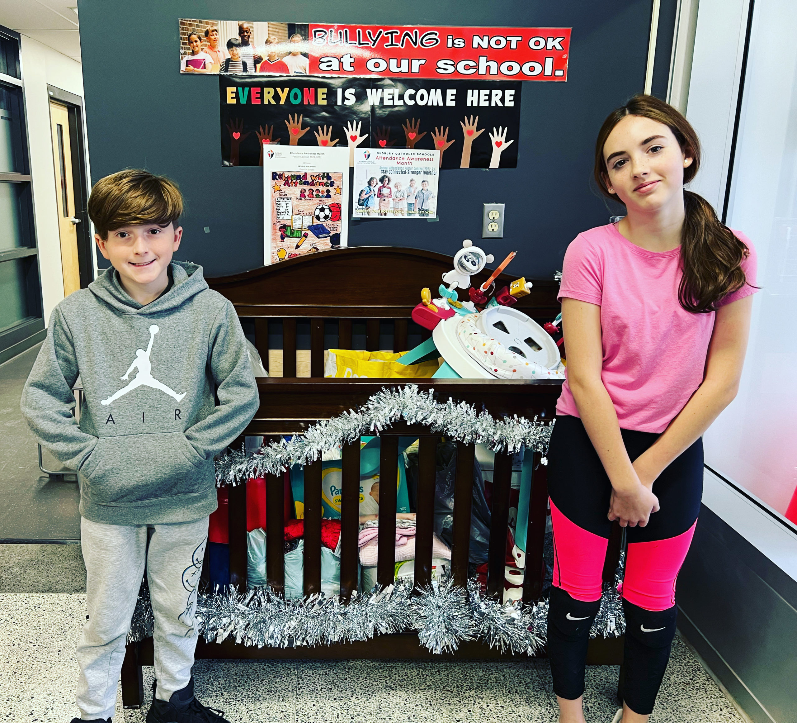 Two students stand near a crib