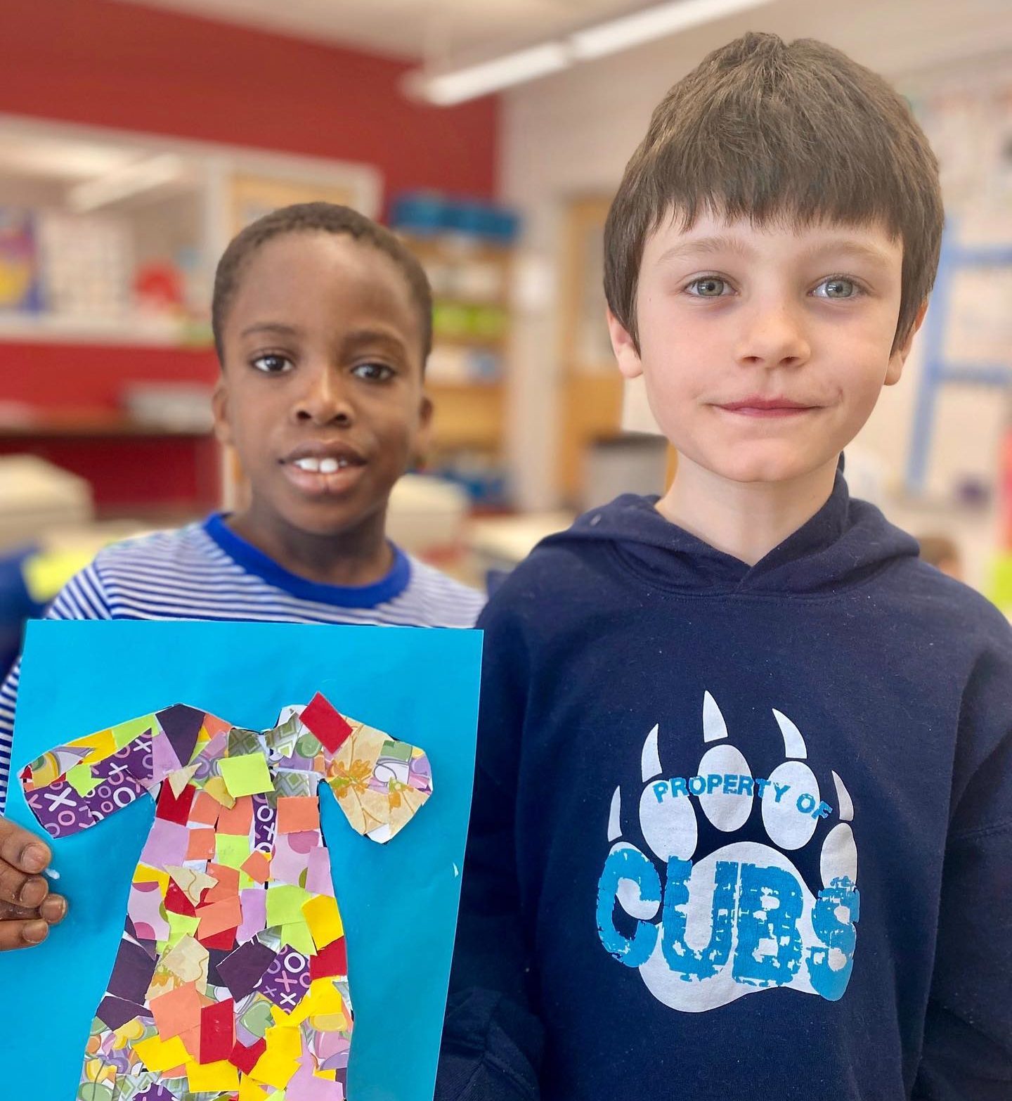 Two students hold up their art.