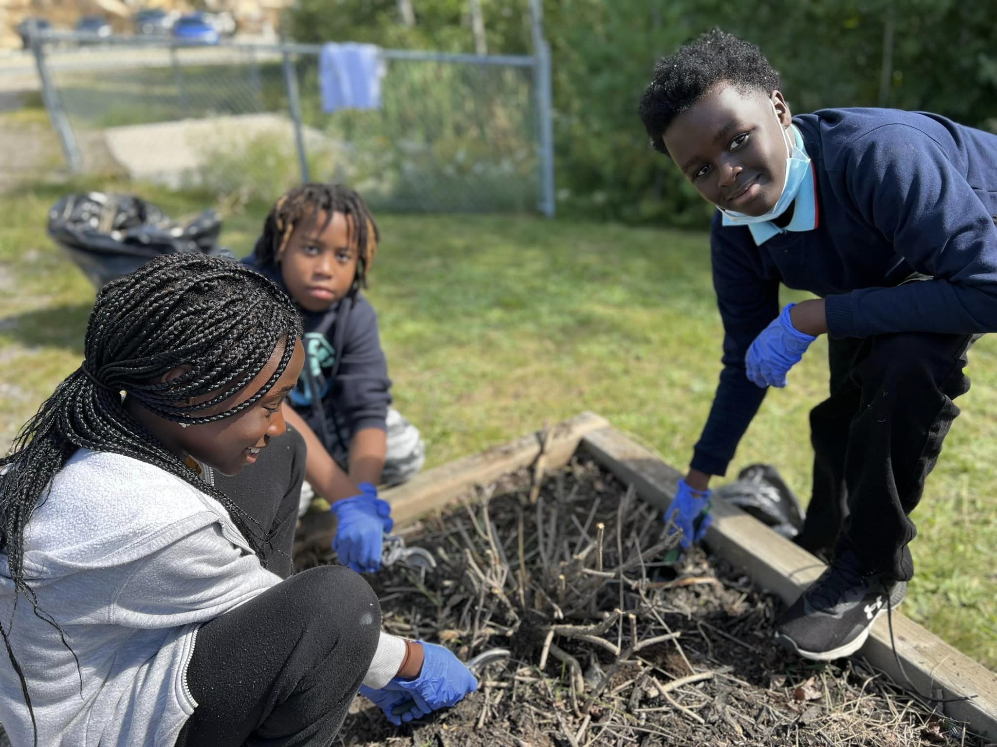 Students de-weeding and cleaning a garden bed at a school.